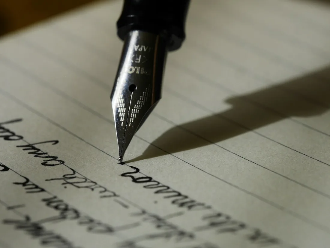 An open notebook being written in with a fountain pen