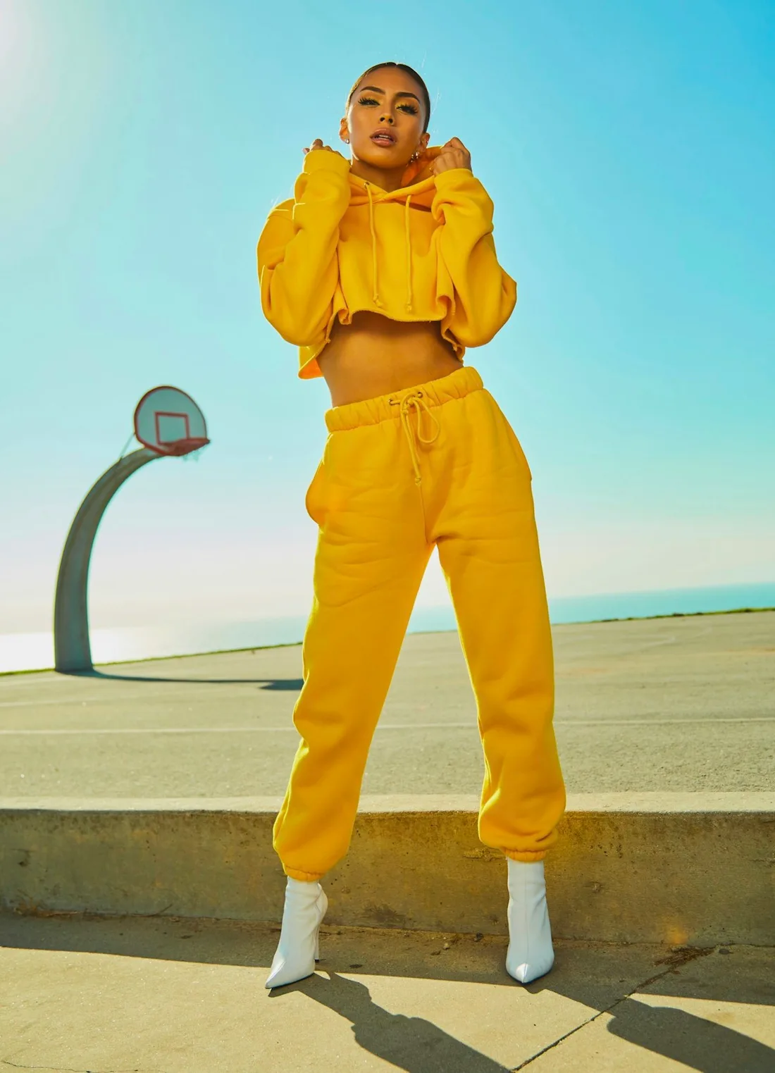 Woman in a yellow outfit on a sunlit outdoor basketball court