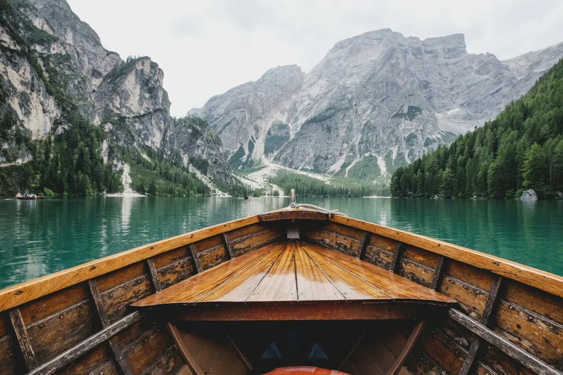 Wooden boat floating on a mountain lake surrounded by steep hills